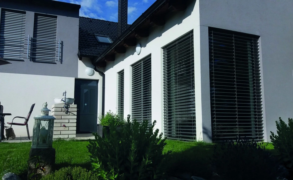 Bílý rodinný dům s antracitovými venkovními žaluziemi