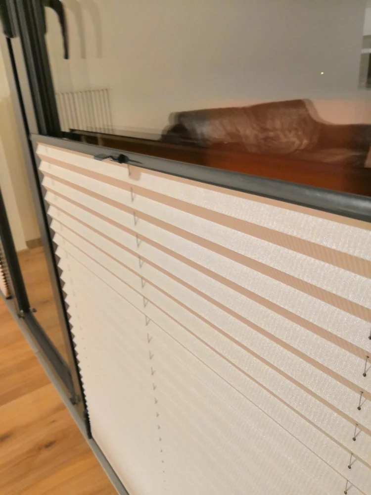 Detail světlého plisé stínění v interiérovém okně